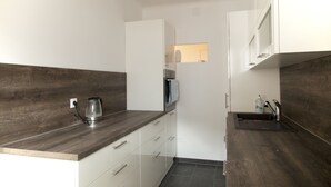 A compact kitchen with a dark wood countertop, white cabinets, and a small sink.