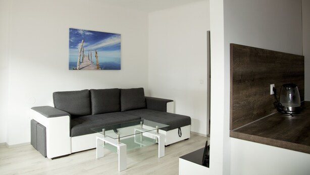 A modern living room with a gray sectional sofa, a glass coffee table, and a wooden accent wall.