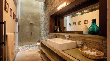 Un baño moderno con un lavamanos grande, un espejo y una zona de ducha.