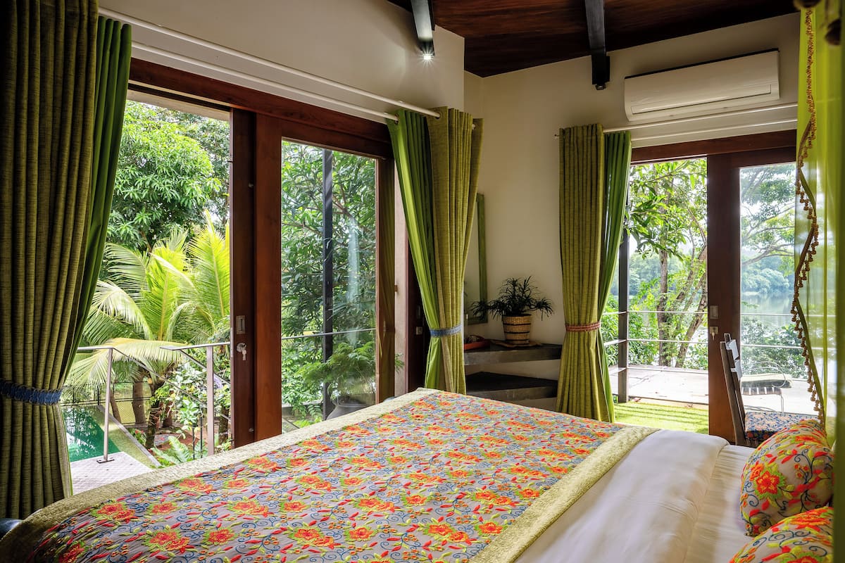 Une chambre avec un grand lit, des rideaux verts et une vue sur un paysage verdoyant.