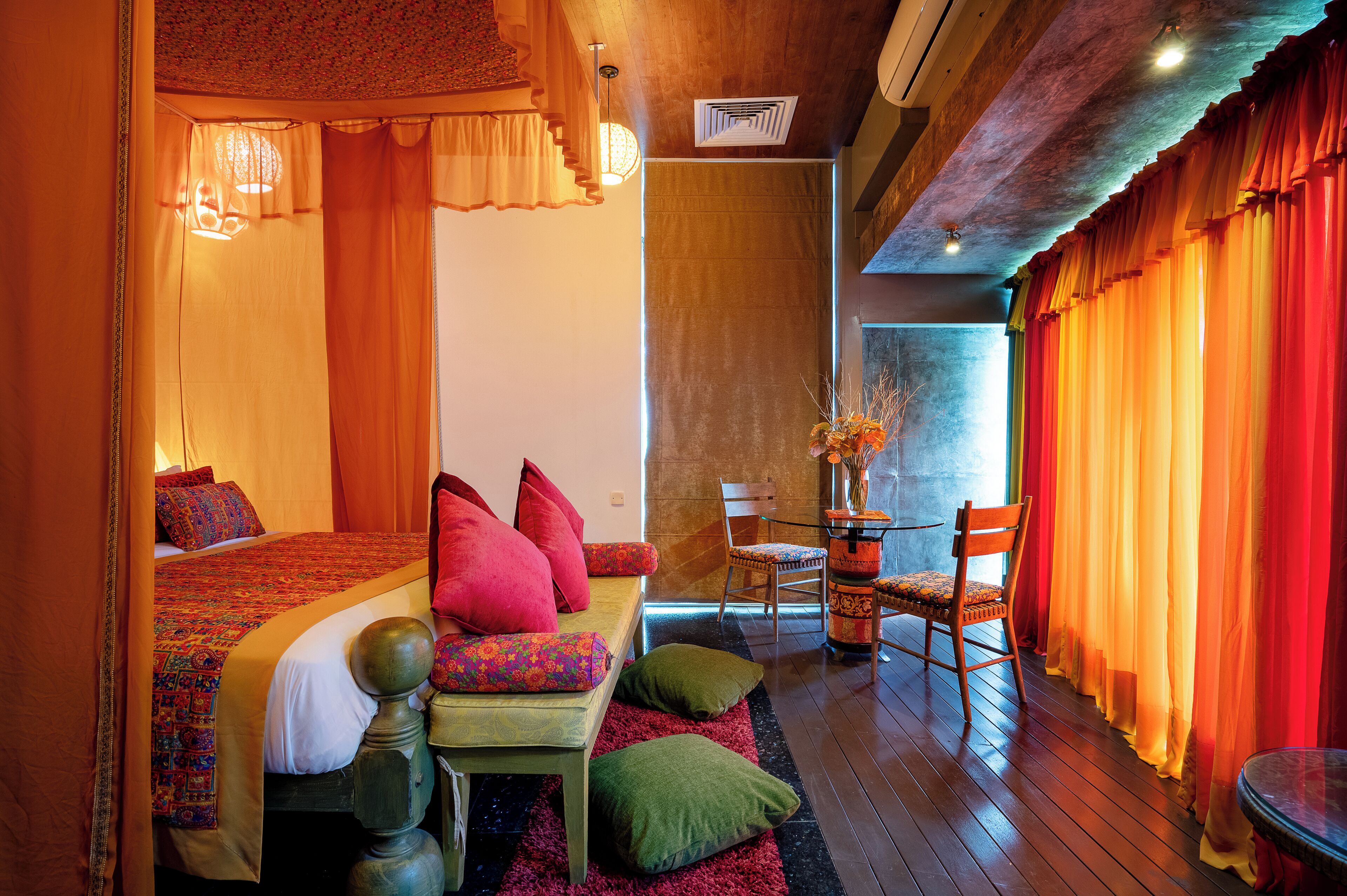 Ein Zimmer mit einem Bett, einem Schlafsofa, einem Esstisch mit Stühlen und einem kleinen Tisch mit einer Vase.