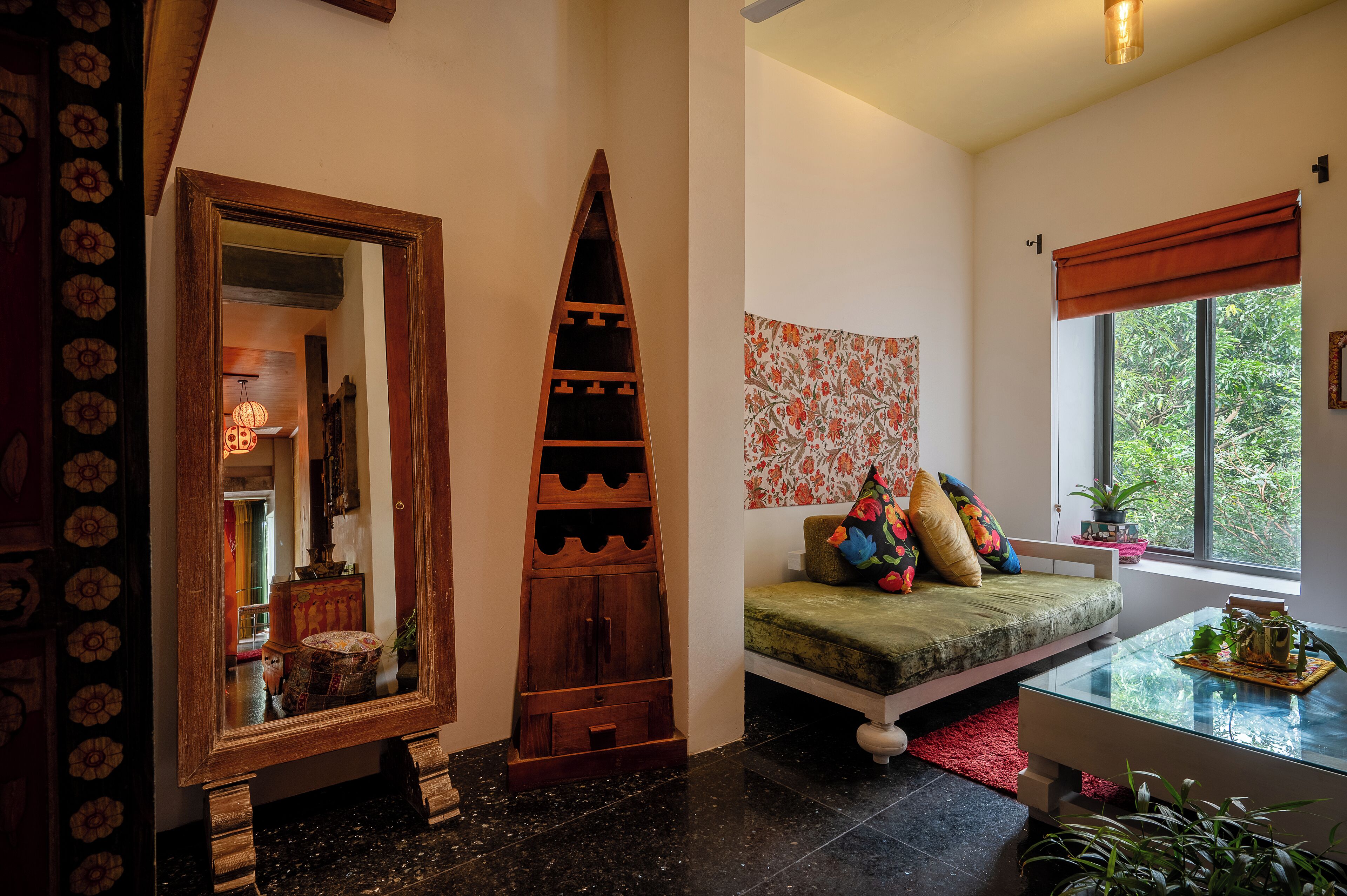 A room with a sofa, a glass coffee table, a wooden cabinet, and a window with a view of greenery.