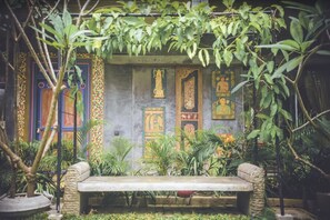 A garden with a stone bench, potted plants, and a wall with decorative panels. - Aathma Colombo House (Sri Jayawardenepura Kotte)