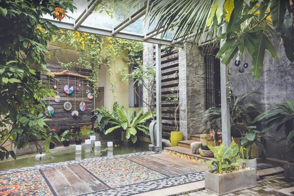 A tranquil indoor garden with a small water feature, potted plants, and a decorative wall with hanging ornaments. - Aathma Colombo House (Sri Jayawardenepura Kotte)