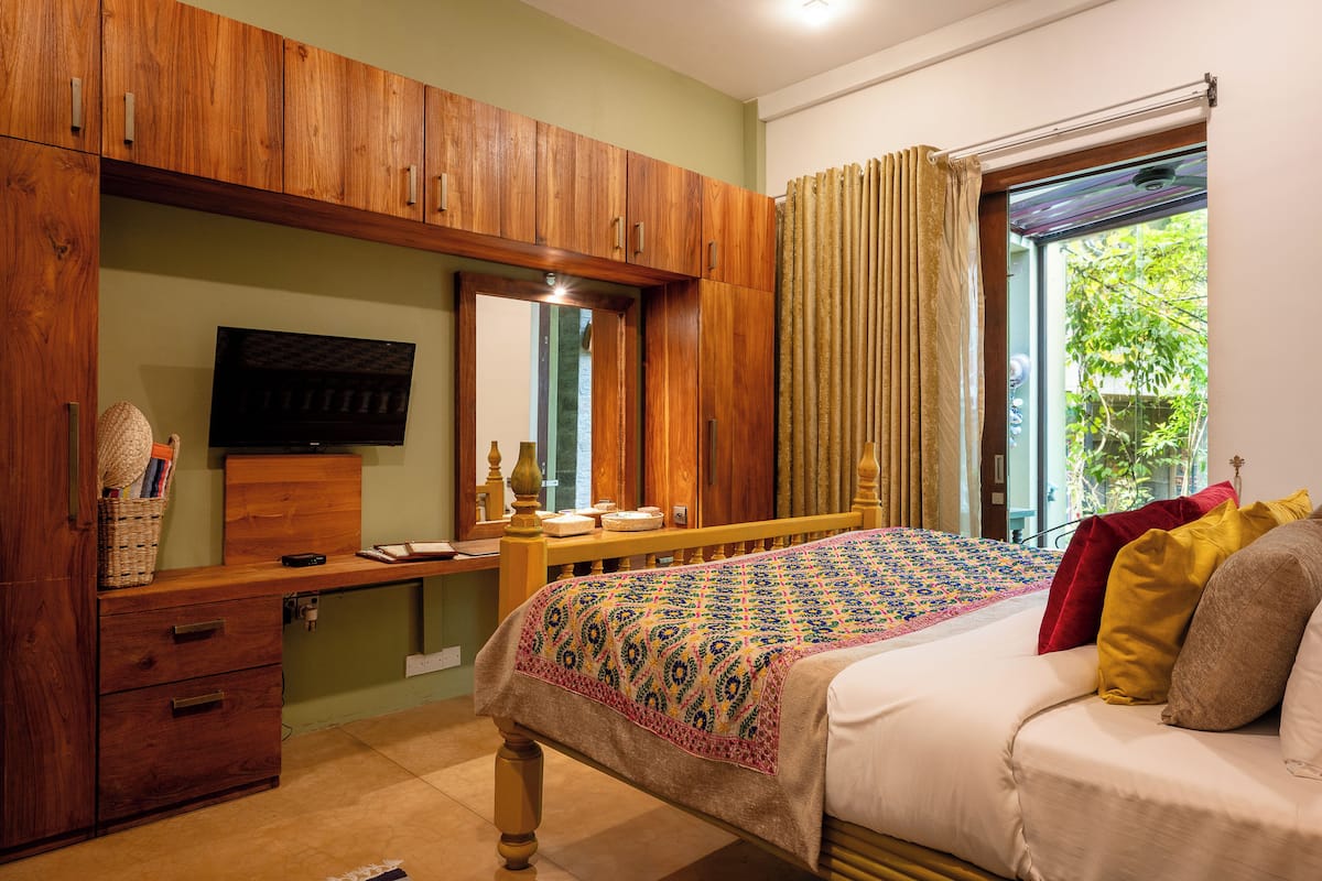 Une chambre à coucher comprenant un lit, une armoire en bois, un bureau et un téléviseur.