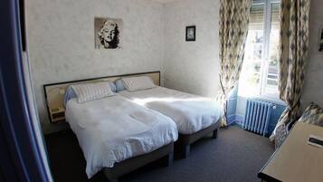 Un dormitorio con dos camas, una ventana con cortinas, un radiador y un cuadro en la pared.