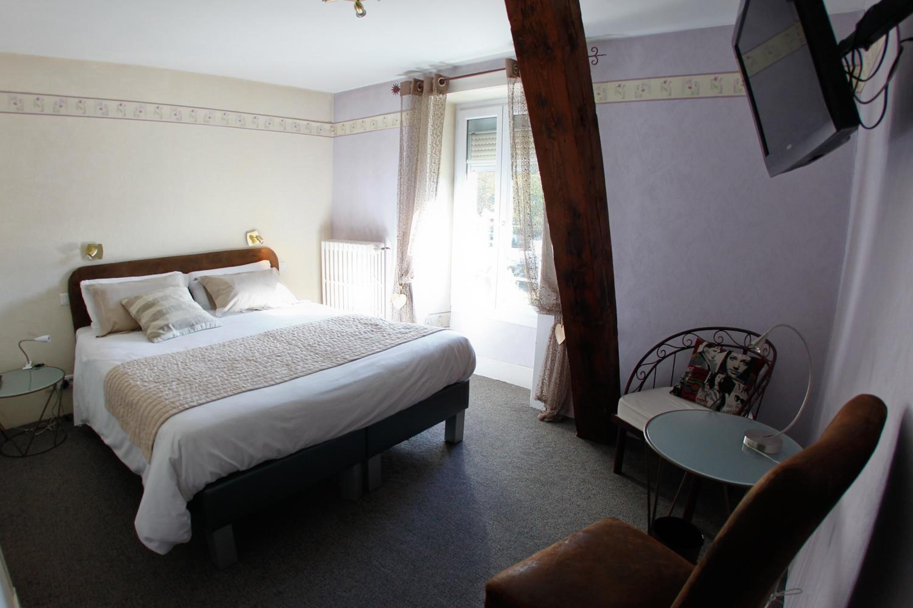 A bedroom with a bed, bedside table, chair, and a small table with a chair.
