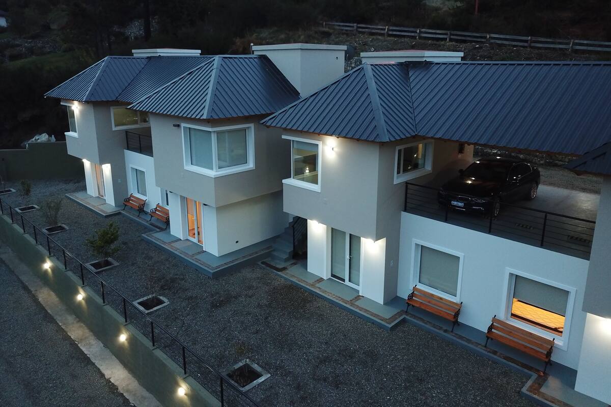 Uma casa moderna de dois andares com garagem, área de estar ao ar livre e entrada por acesso carroçável.