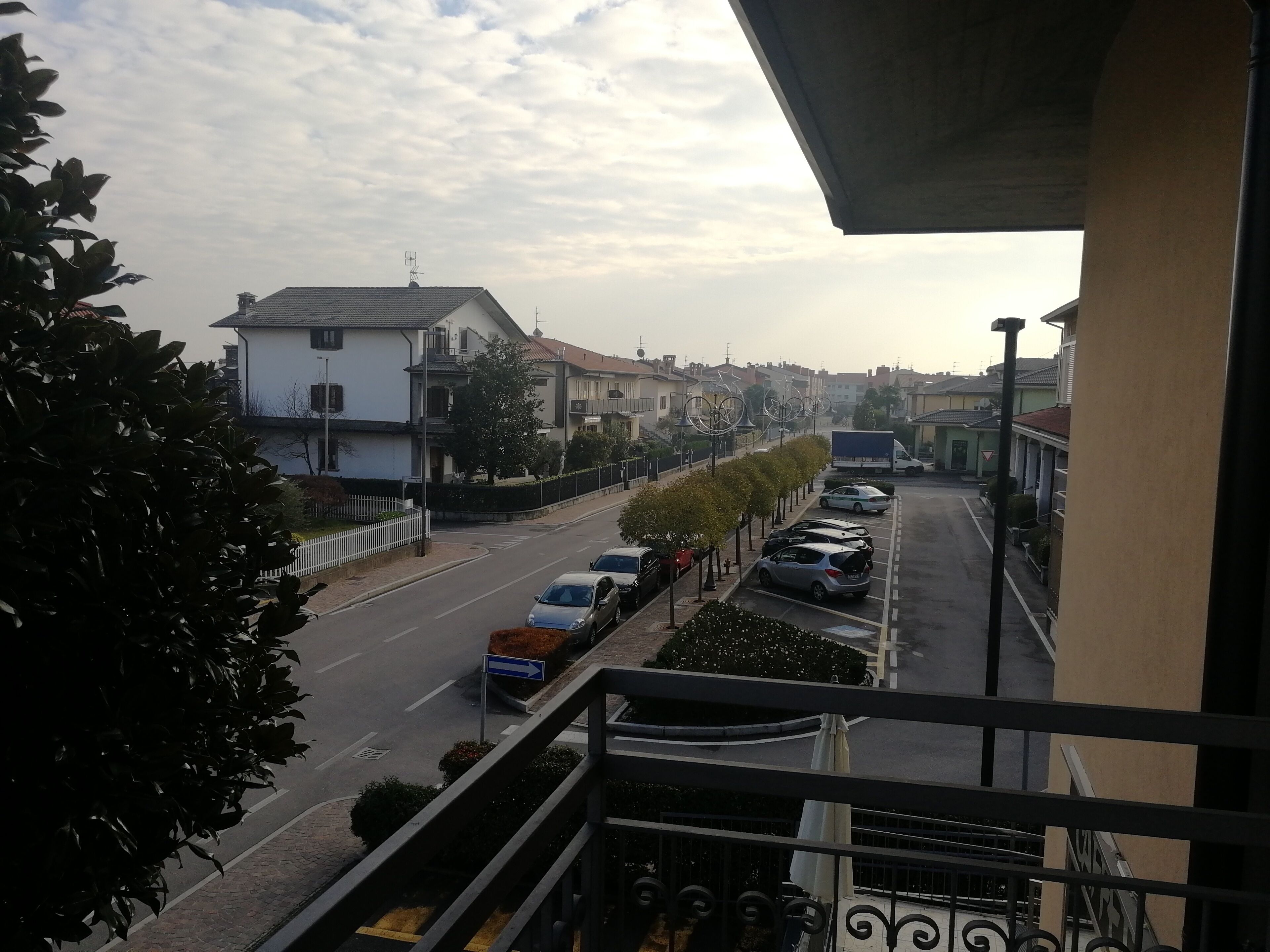 Eine Wohnstraße mit parkenden Autos, einem weißen Haus und blauem Himmel.