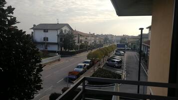 Eine Wohnstraße mit parkenden Autos, einem weißen Haus und blauem Himmel.