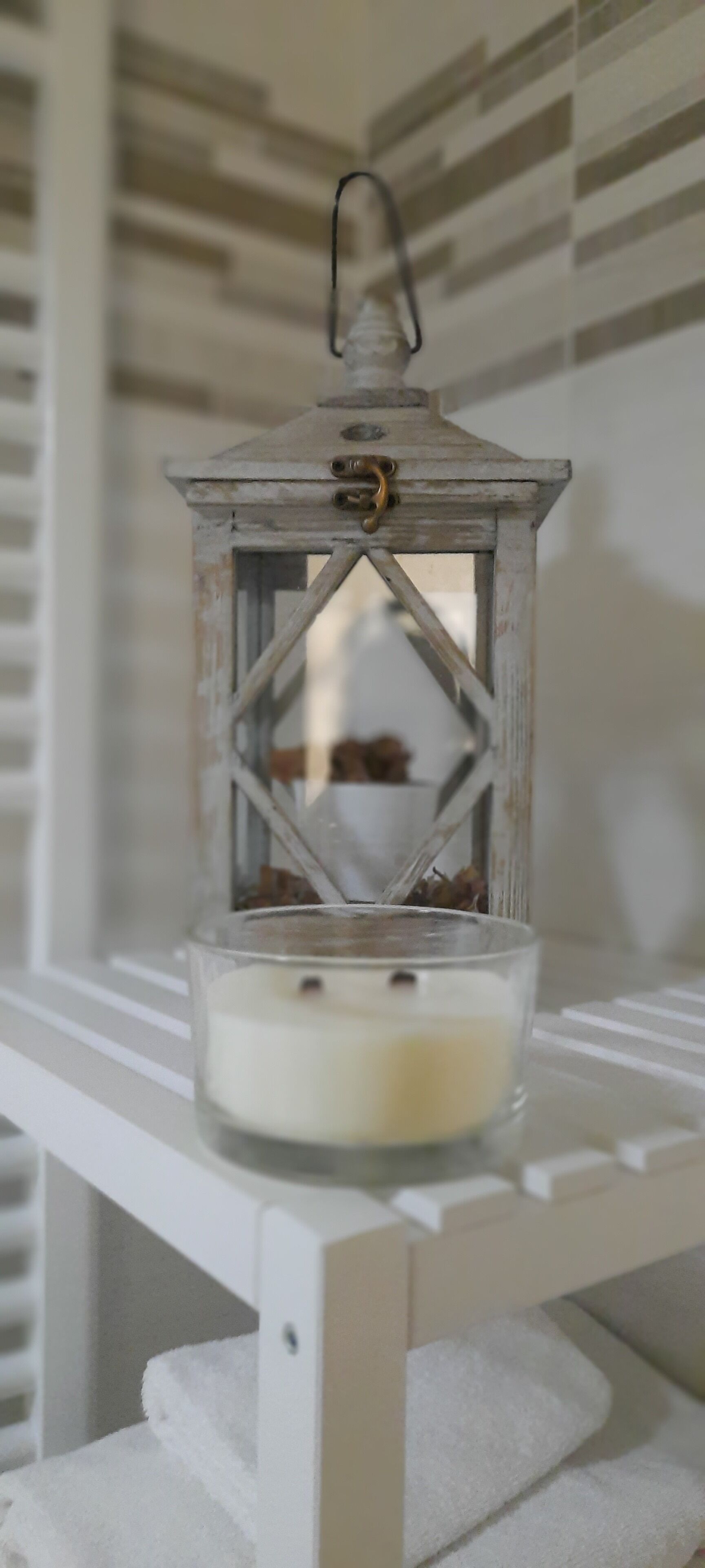 Une table blanche sur laquelle se trouve un chandelier en verre contenant une bougie blanche.