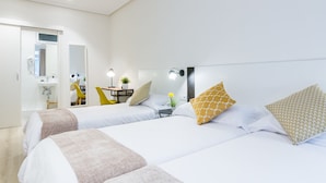 A hotel room with two beds, a bathroom, and a small sitting area with a chair and table. - Pensión BUENPAS (San Sebastián)