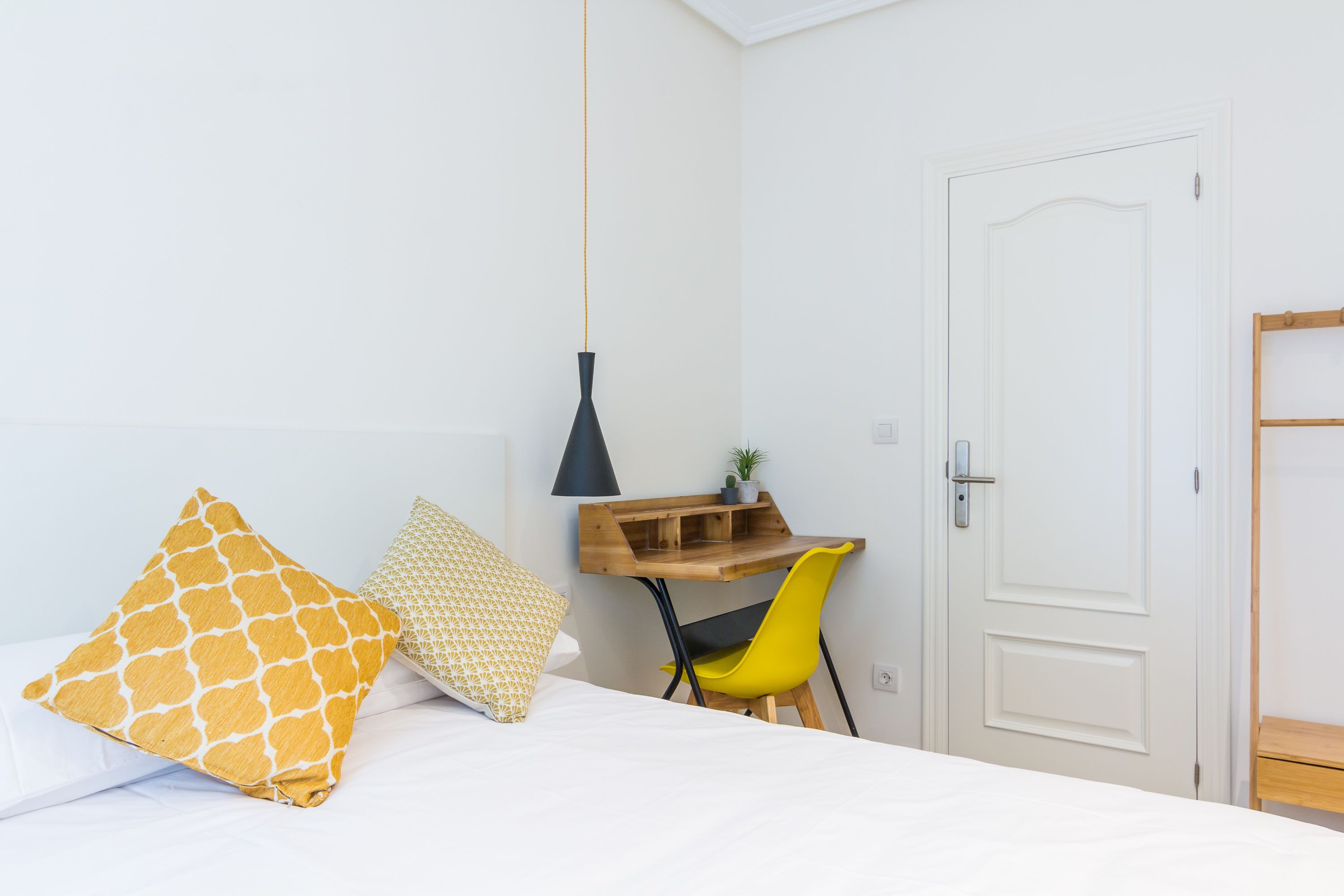 A bedroom with a bed, a desk, and a chair.