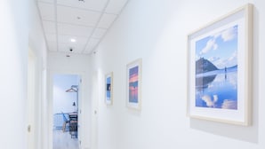 A hallway with framed pictures on the walls, a door leading to a room with a table and chairs, and a ceiling with recessed lighting. - Pensión BUENPAS (San Sebastián)