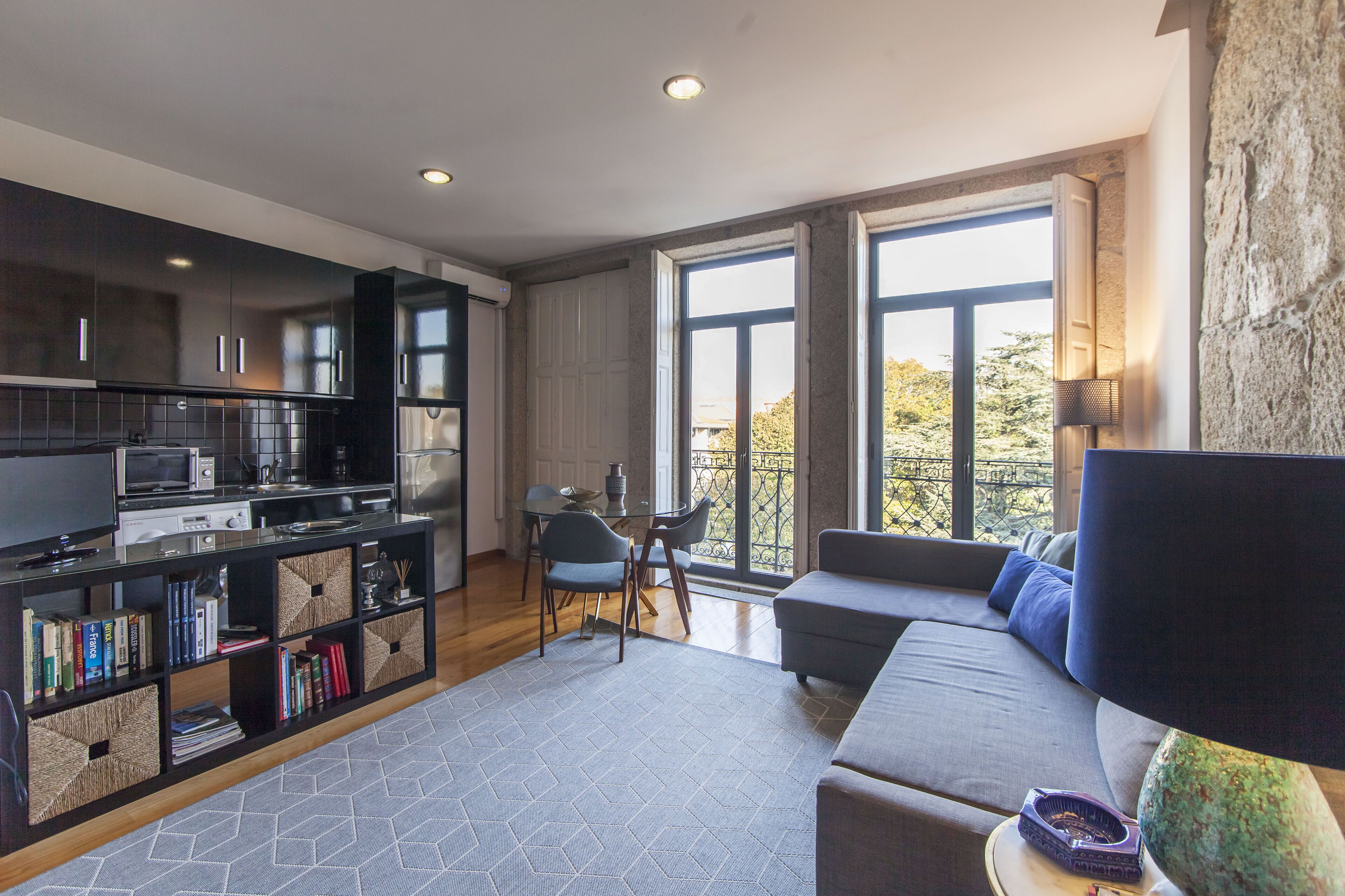 A modern living room with a sofa, a TV, a bookshelf, and a dining area with chairs and a table.