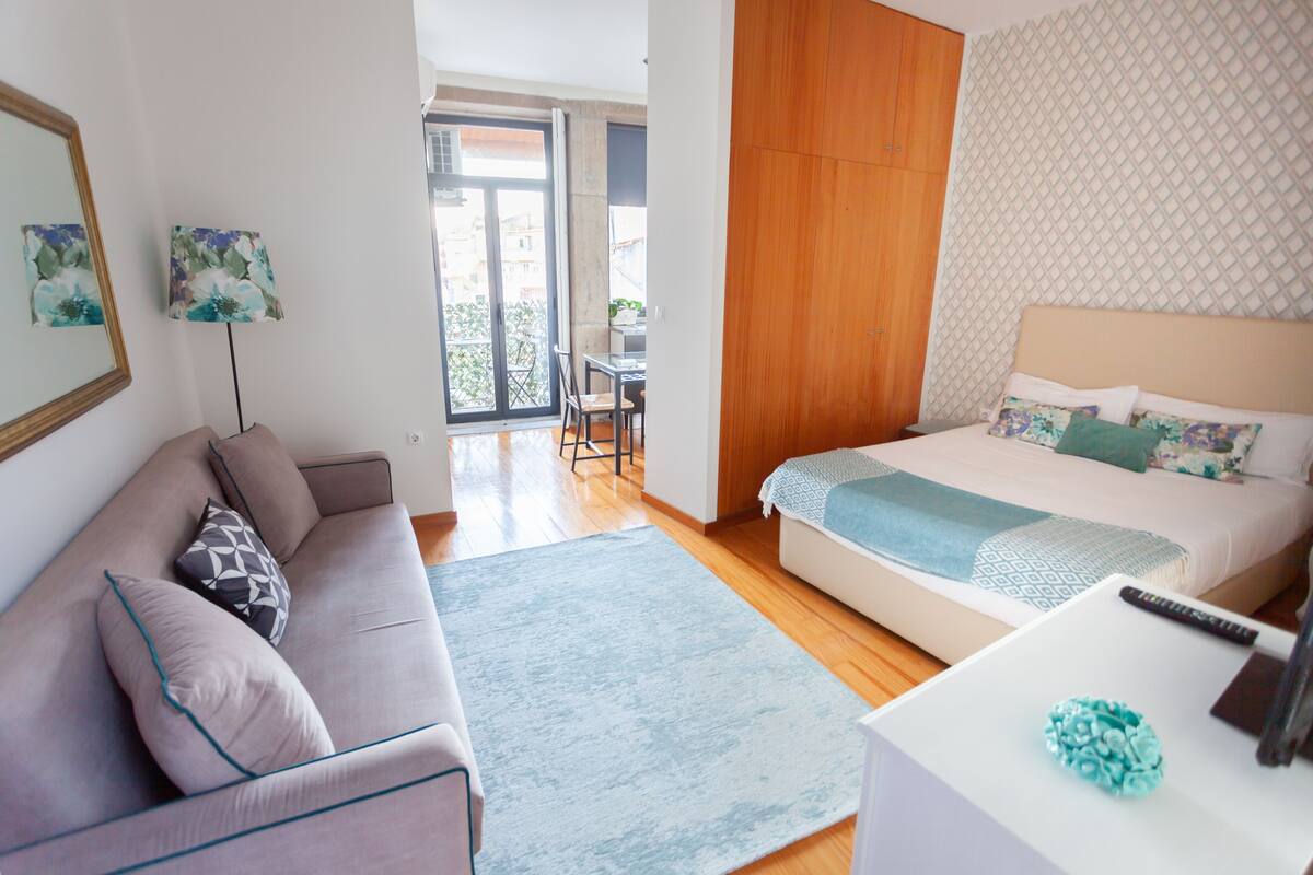 Une chambre d’hôtel moderne avec un canapé, un lit, une petite table et un balcon offrant une vue.