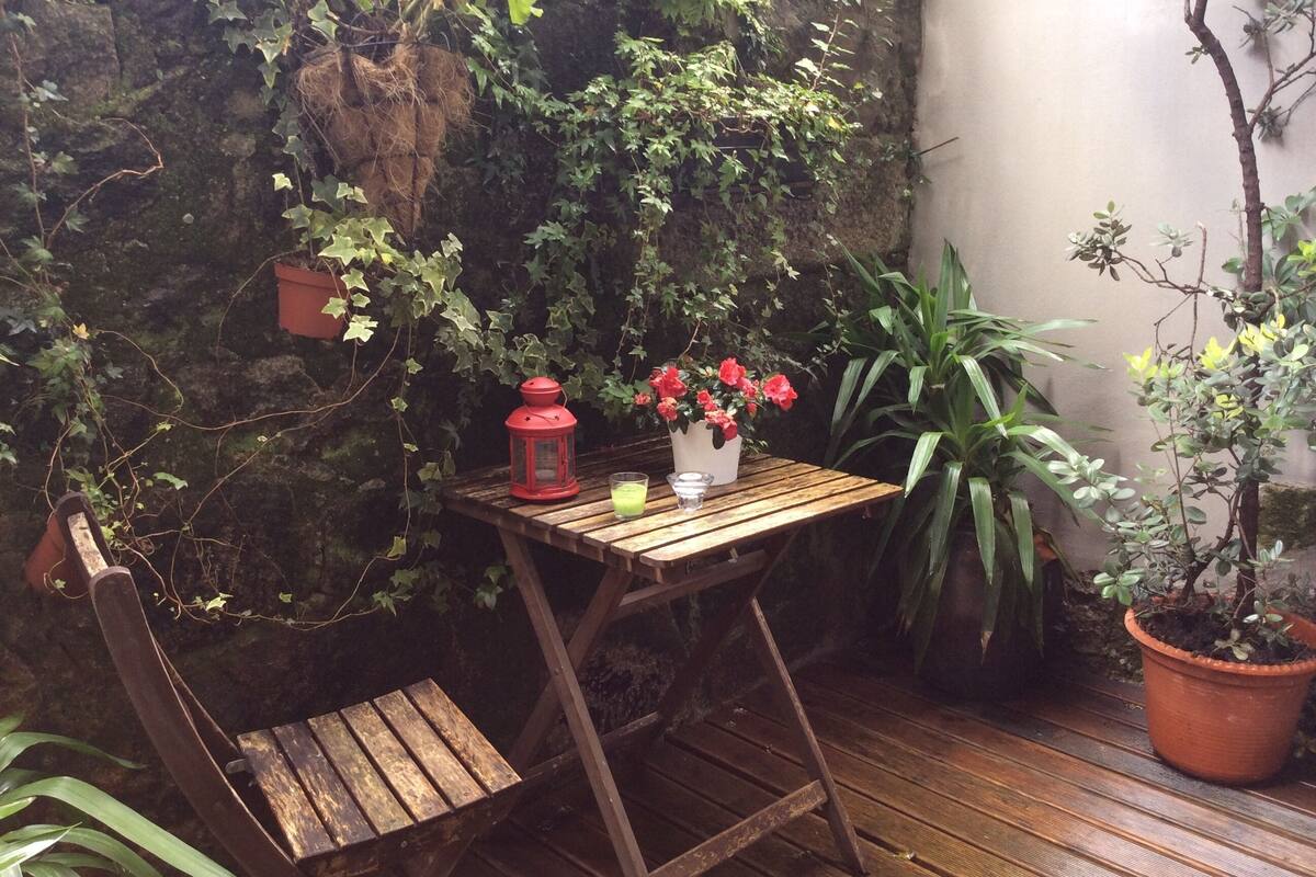 Une table en bois, sur laquelle se trouvent une lanterne rouge et un pot de fleurs avec des fleurs rouges.