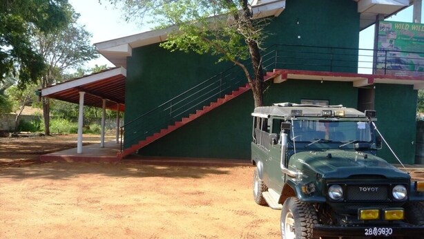 A green building with a covered area and a staircase. - Palugaha Pilgrim Resort (Kataragama)