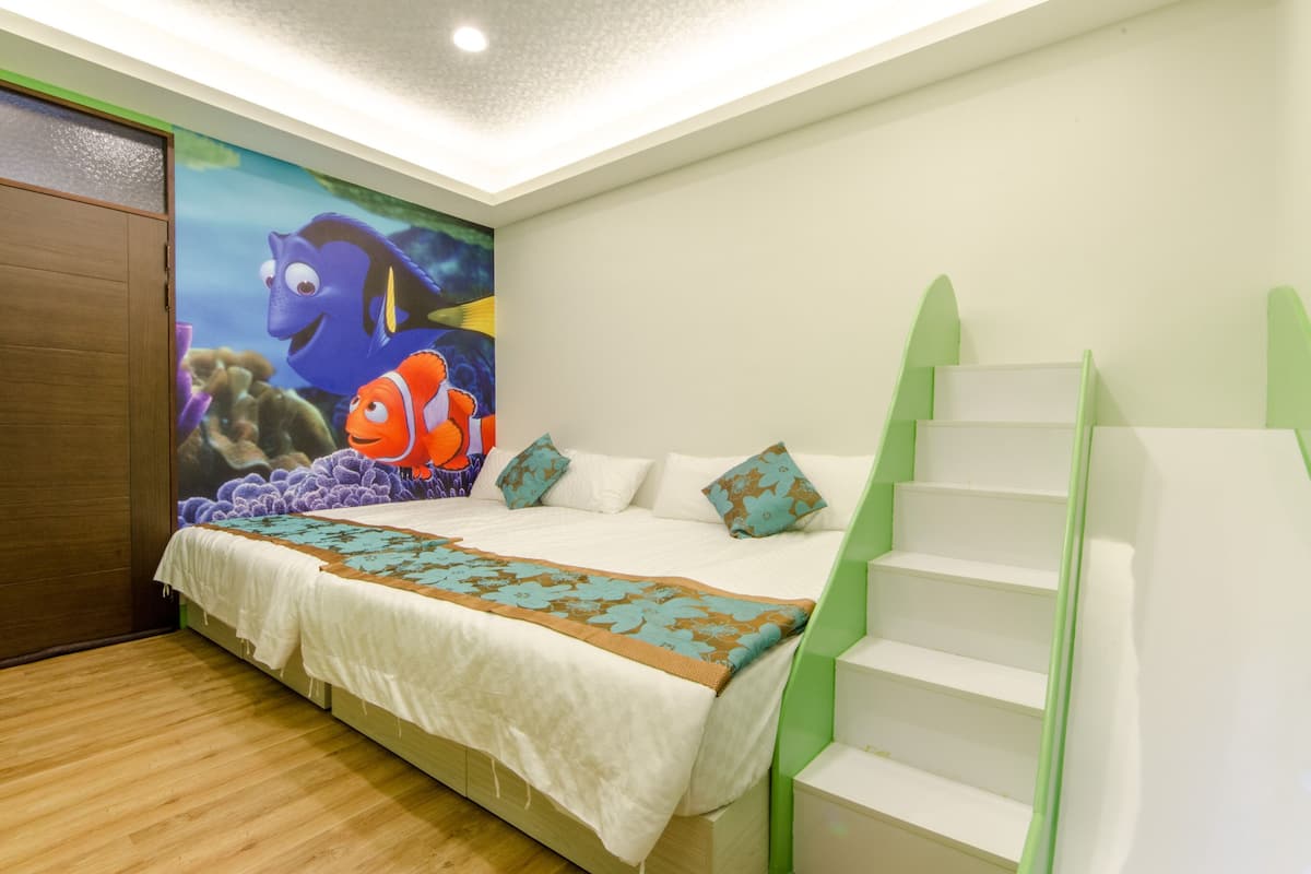 A bedroom with a bed, a mural of fish, and a staircase.