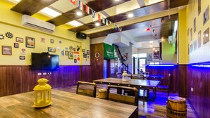 A restaurant interior with wooden tables and benches, a television mounted on the wall, and various decorations including flags and framed pictures. - DAN DAN Bed and breakfast (Dongshan)