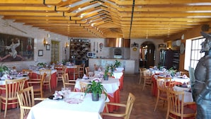 Un ristorante con travi in legno, pareti in mattoni e tavoli apparecchiati per la cena.
