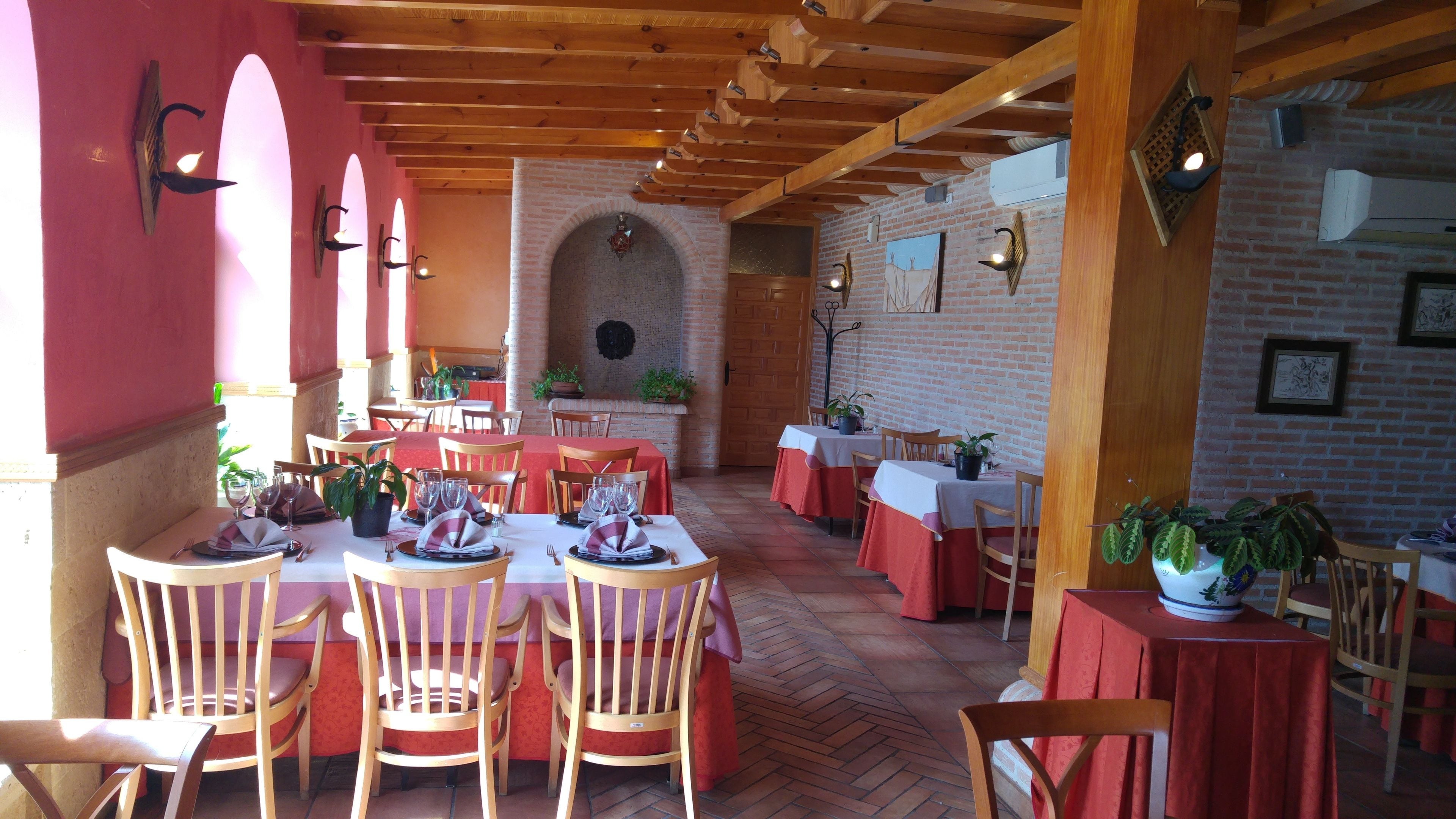 Un restaurante con mesas y sillas de madera, paredes de ladrillo y plantas en macetas.