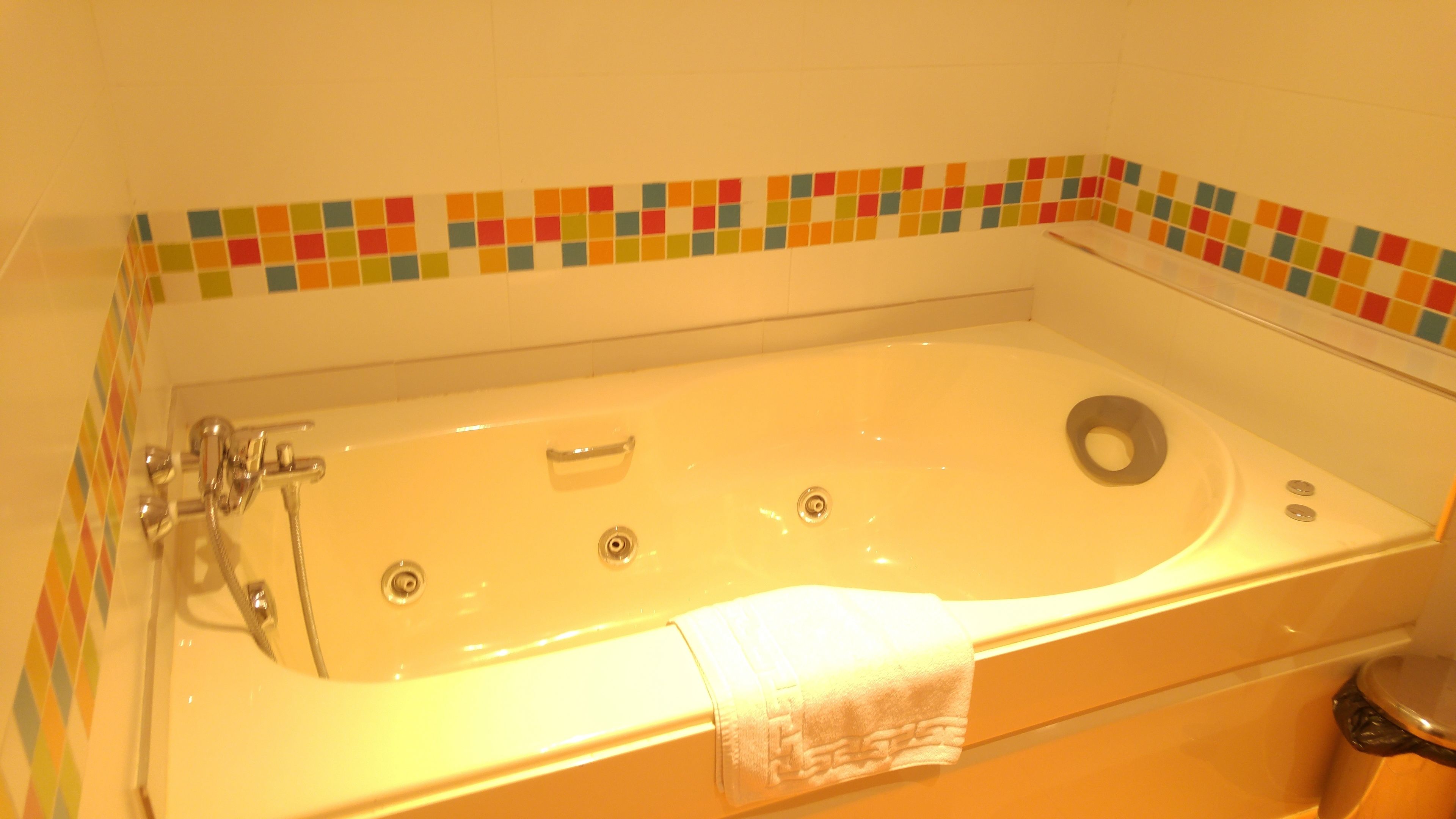 A bathtub with a showerhead, a drain, and a towel.