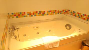 Una bañera con cabezal de ducha, desagüe y una toalla.