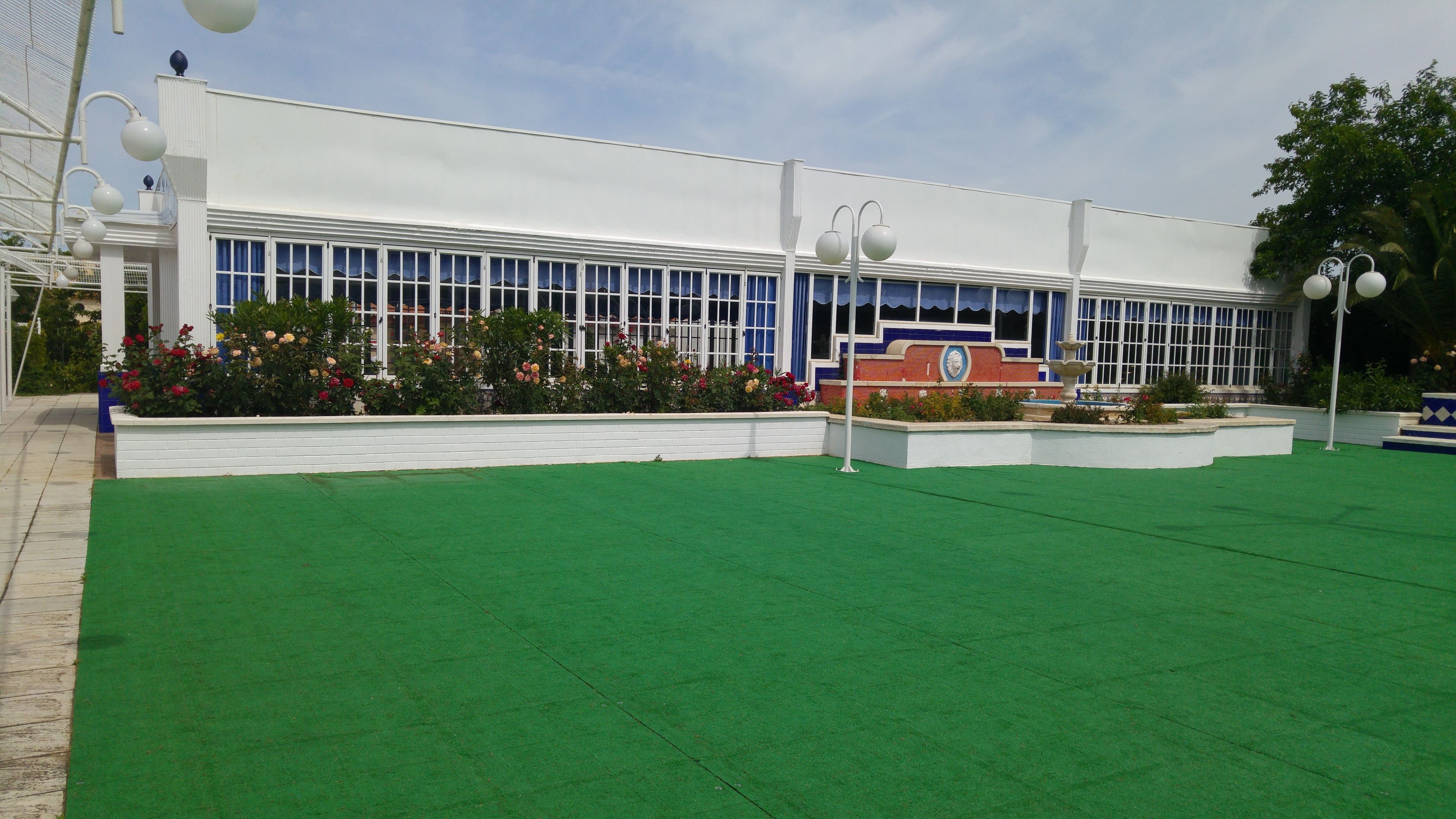 A building with a white facade, large windows, and a central courtyard with green artificial grass.