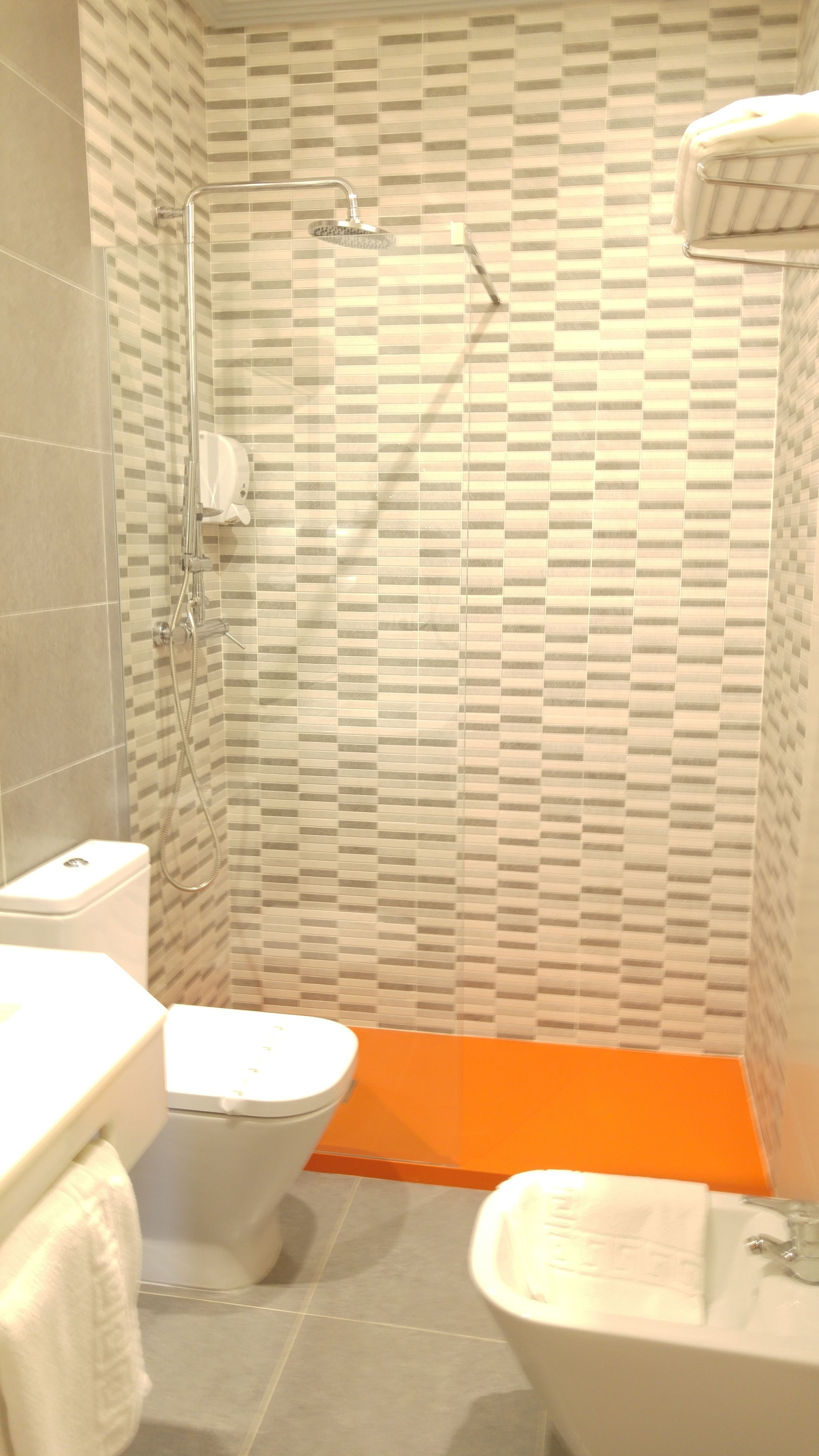 A bathroom with a shower, toilet, and sink.