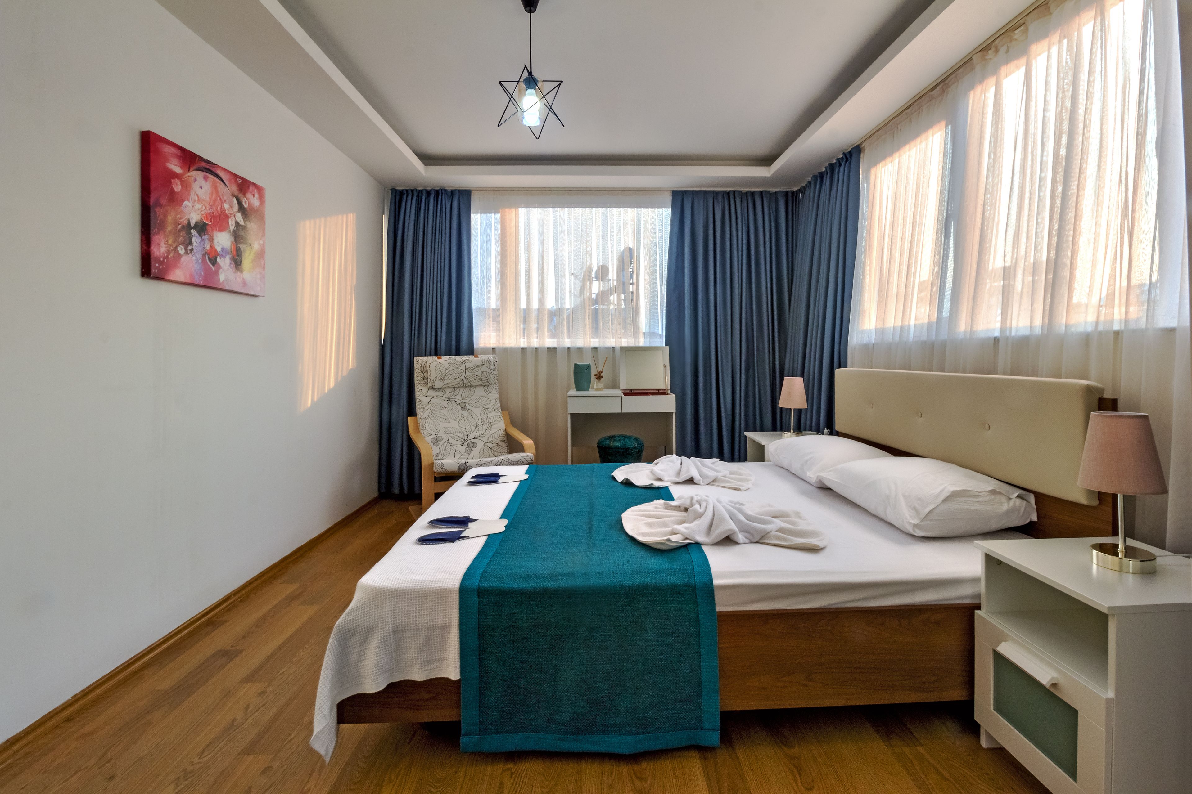 Een hotelkamer met een bed, een stoel, een bureau en een raam met gordijnen.