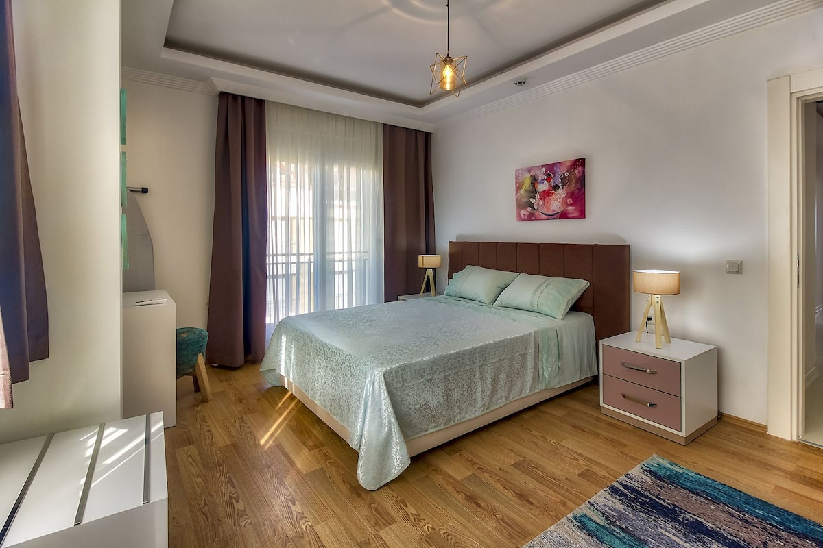 A bedroom with a bed, bedside tables, a lamp, and a painting on the wall.
