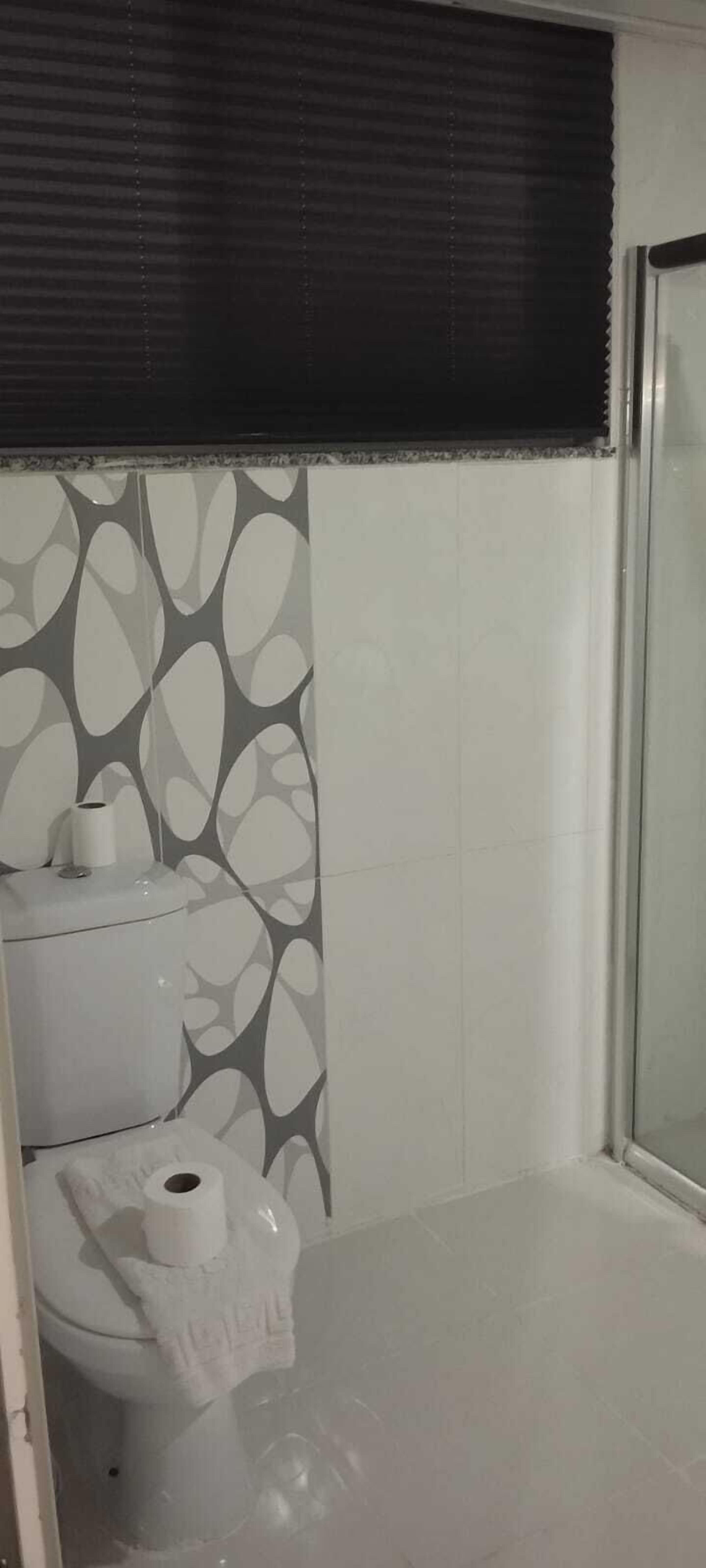 Une salle de bain comprenant des toilettes, un rouleau de papier toilette et un espace douche.