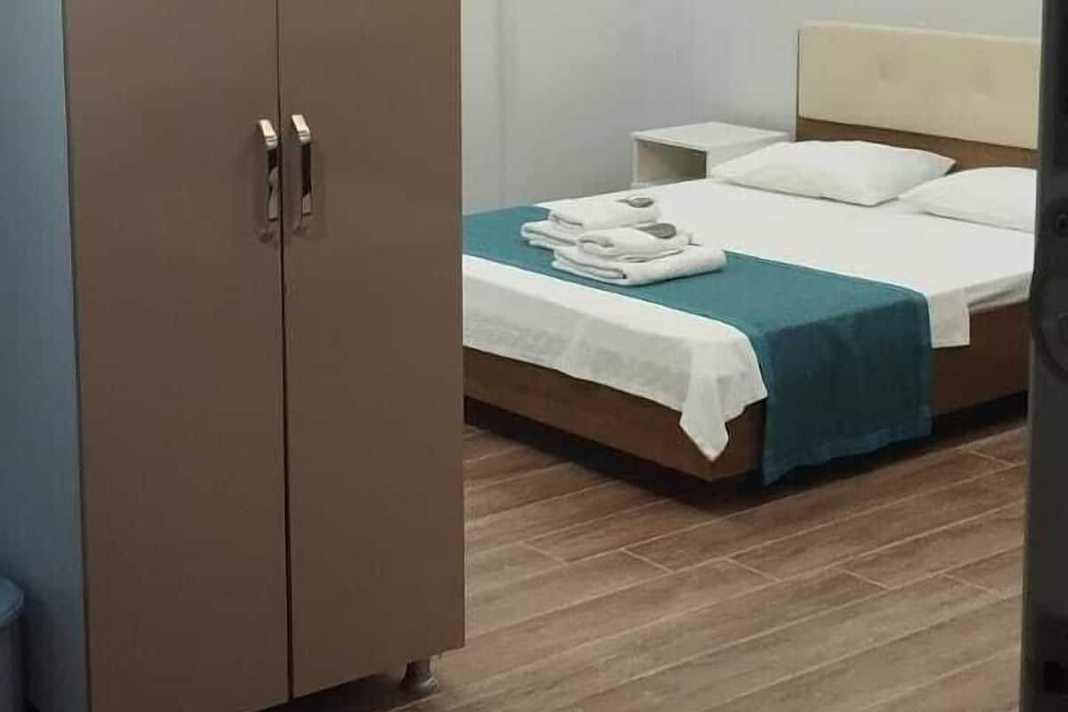 A bedroom with a bed, a wardrobe, and a nightstand.