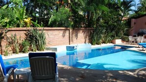 A swimming pool with lounge chairs, surrounded by a brick wall and lush greenery. - Casita Bendon by Las Palmas (Bucerías)