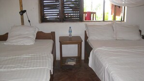 Une chambre avec deux lits simples, une petite table en bois et une fenêtre avec des volets.
