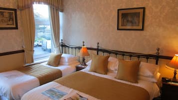 A hotel room with two beds, a window with curtains, a lamp on each side, and a framed picture on the wall.