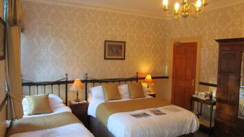 Une chambre d’hôtel avec deux lits, un lustre, une armoire en bois et une porte.