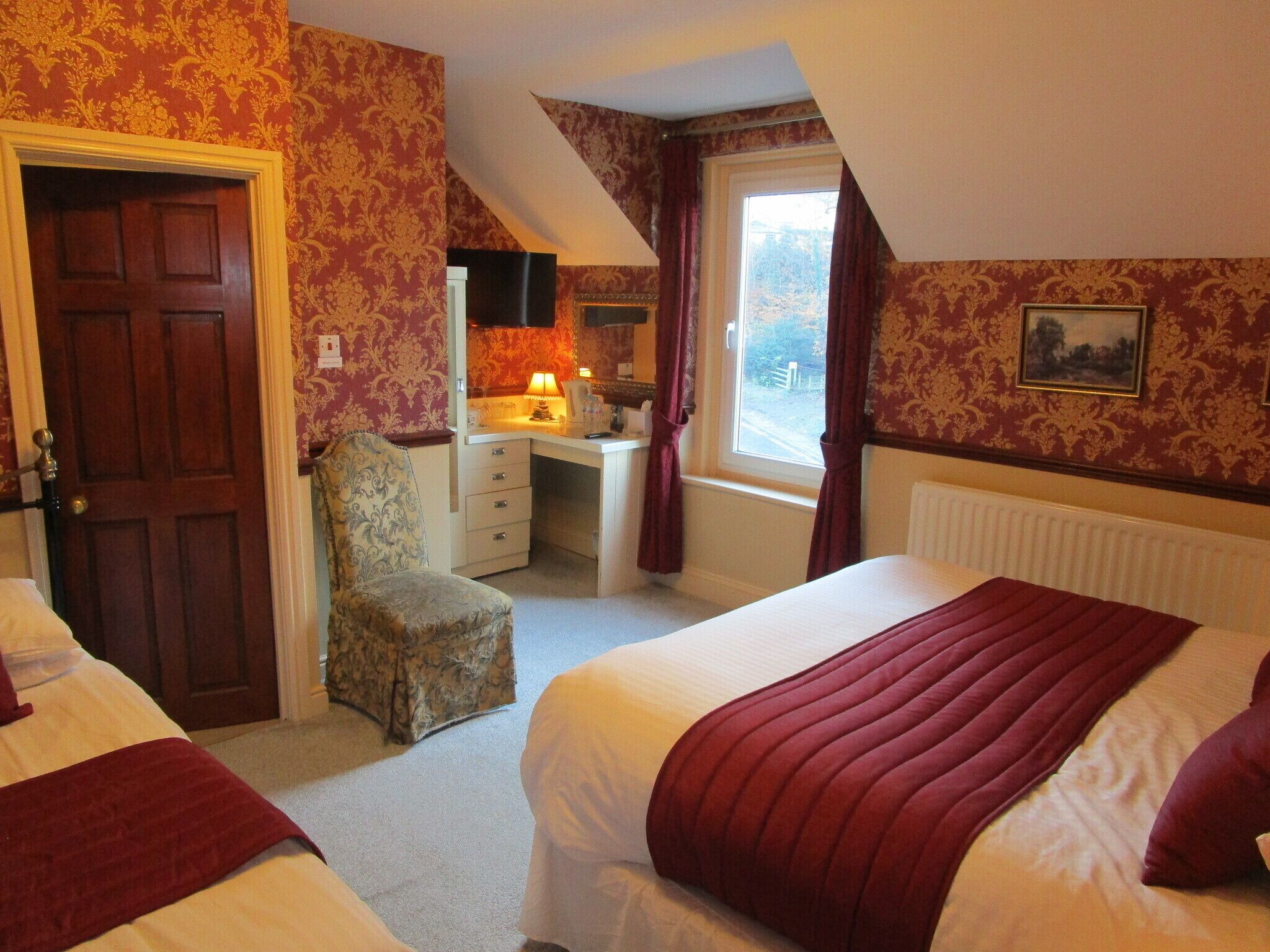 A bedroom with two beds, a desk, and a chair.