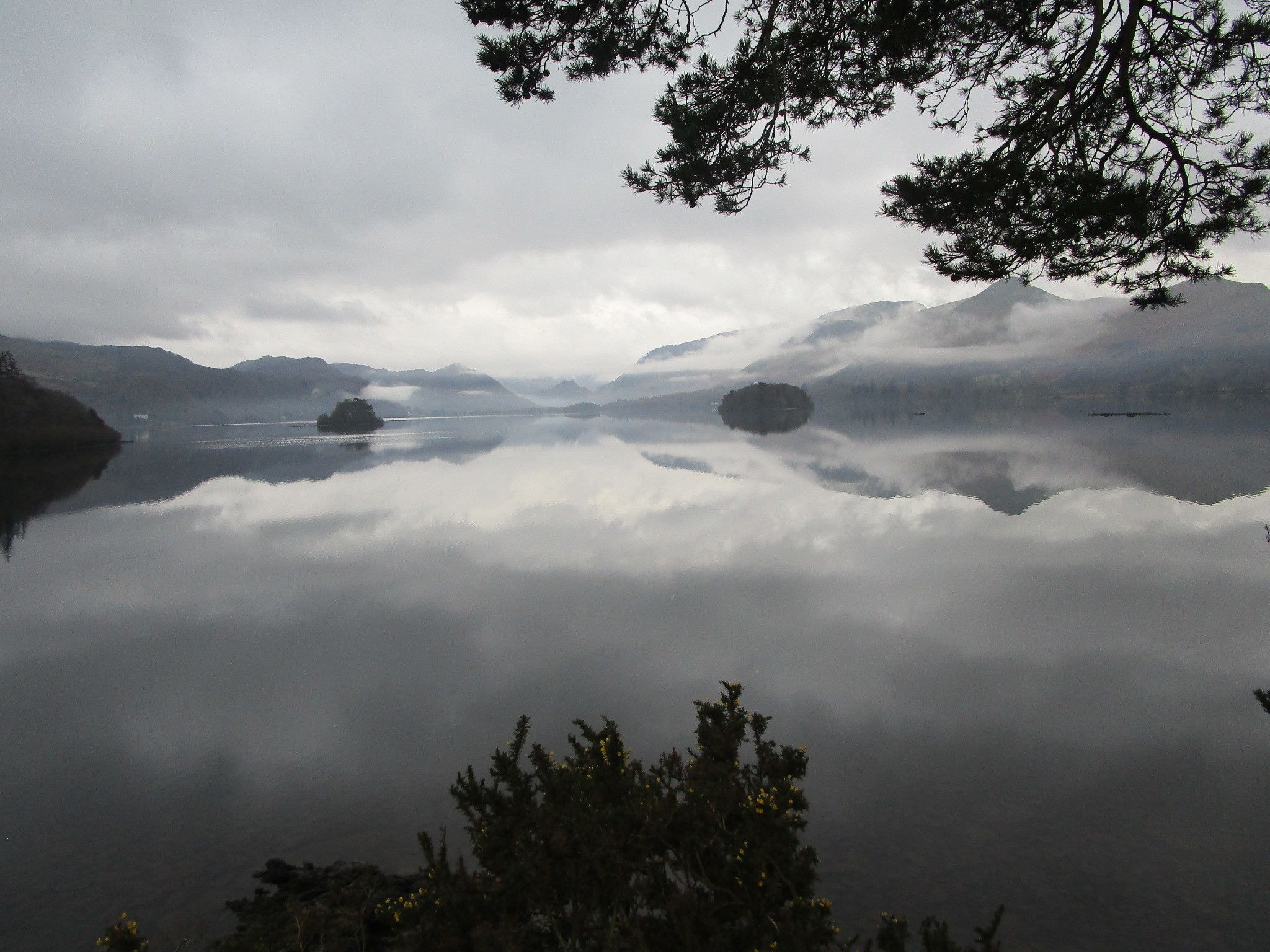 Un lac paisible, entouré de montagnes et d’arbres.