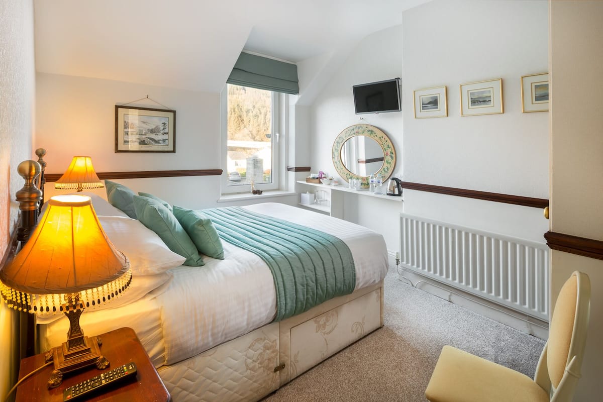 A neatly arranged bedroom with a bed, bedside lamp, and a chair.