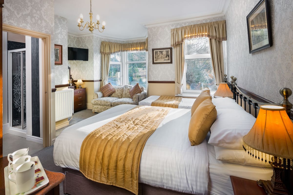 A hotel room with two beds, a sitting area, a television, and a window with a view.