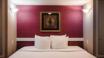 A hotel room with a large bed, two wall-mounted lights, and a framed artwork above the bed.