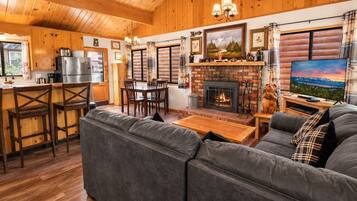 A cozy cabin interior with a fireplace, wooden furniture, and a television.