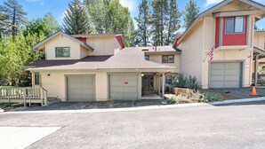 A two-story residential building with a garage, a small porch, and a flag. - Bear Mountain Escape Condo (Big Bear Lake)