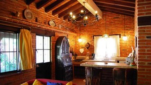 A rustic kitchen with exposed brick walls, a red sofa with yellow and blue cushions, and a bar area with stools.