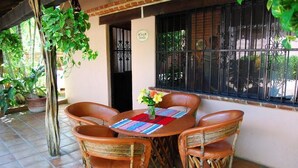 A patio with a round table, four wicker chairs, and potted plants.