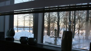 A window with a view of a snowy landscape, bare trees, and a lamp post. - Country Dream guesthouse (Selfoss)