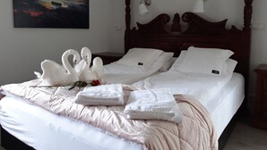 A neatly made bed with white linens, a decorative swan arrangement, and a painting on the wall. - Country Dream guesthouse (Selfoss)