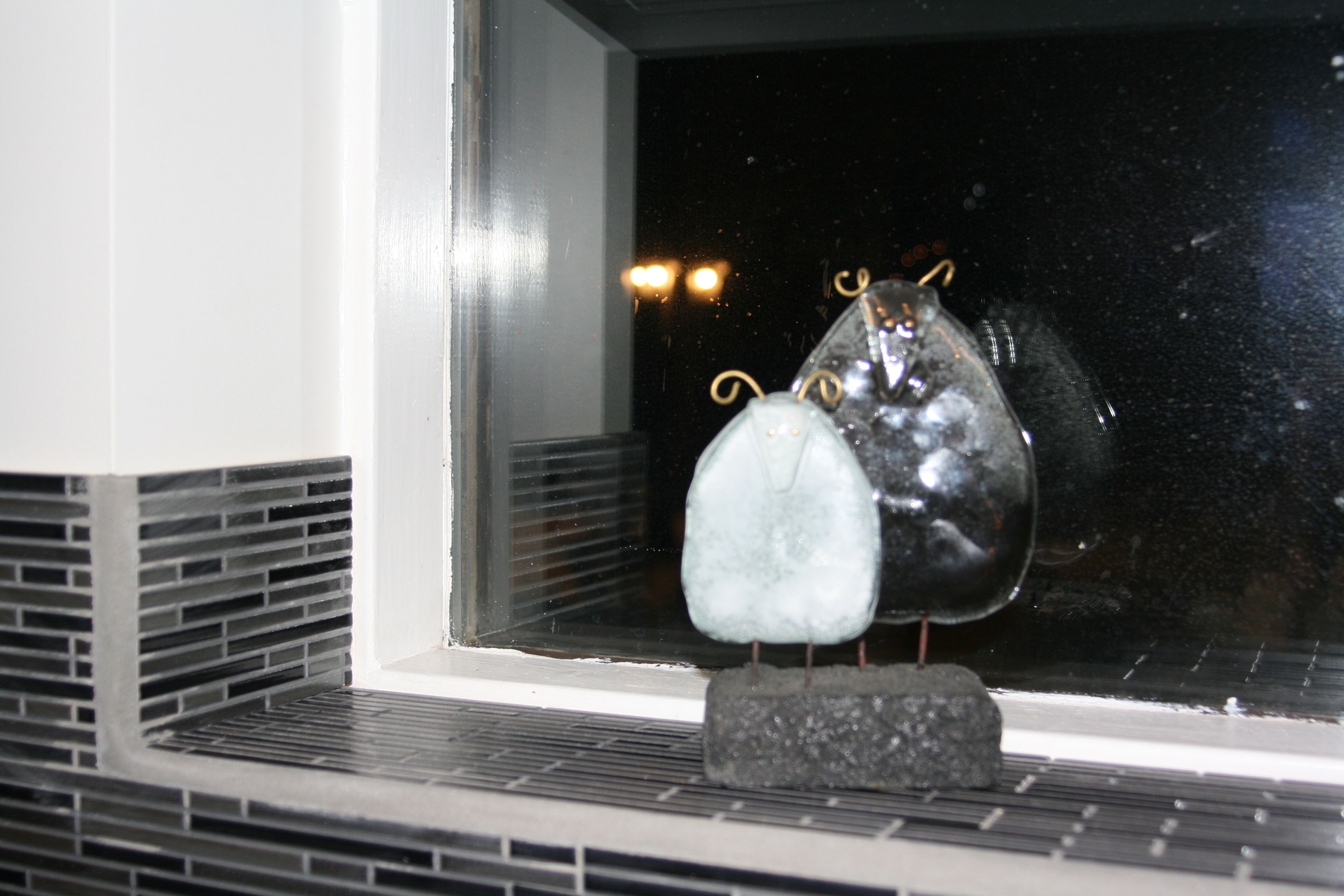 Ein Fenster mit einem dekorativen Glasornament, das zwei kugelförmige Formen und eine kleine Basis zeigt.